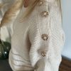 pull beige avec boutons en forme de fleur